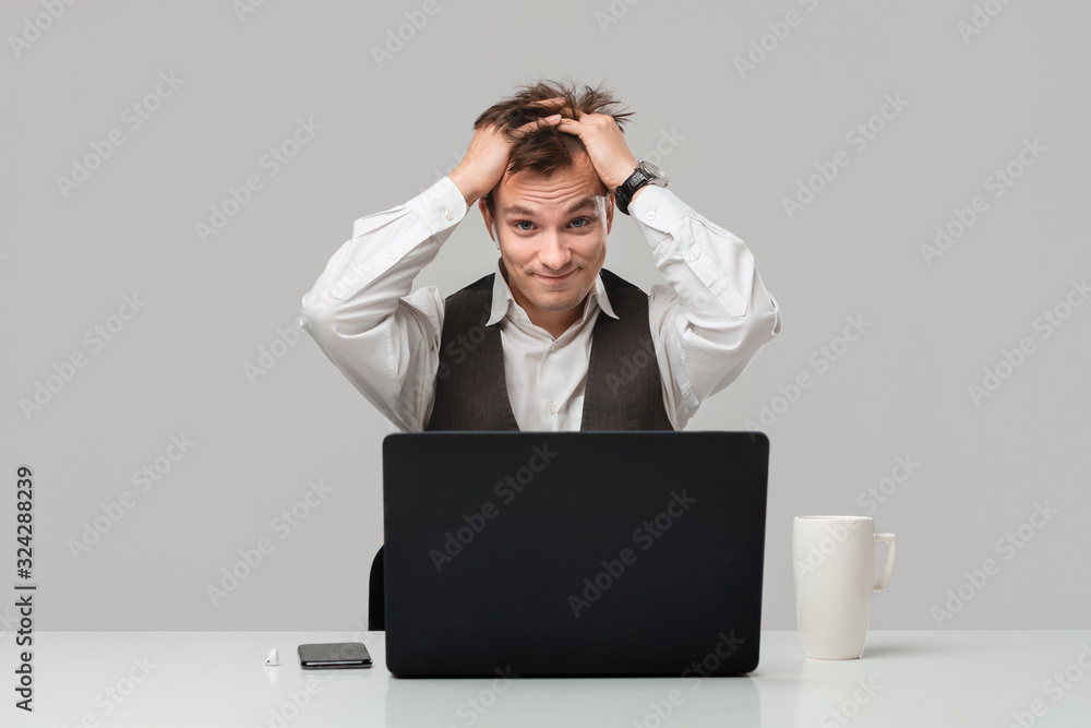 Businessman in a white t-shirt and grey vest is shocked checking information on a laptop Businessman in a white t-shirt and grey vest is shocked checking information on a laptop