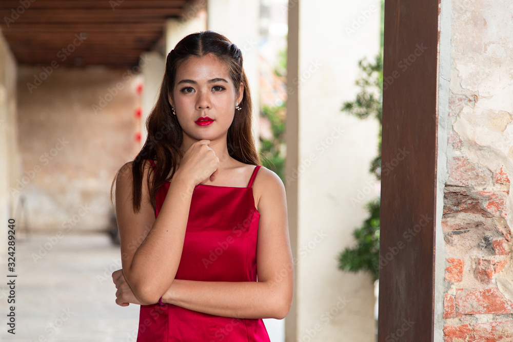 Close up portrait of smiling woman red dress standing and looking camera.  Portrait of satisfied and successful lady outdoor.