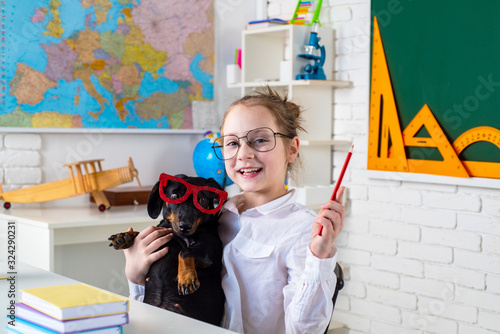 Funny puppi and pupil. Child girl with puppi. Happy smiling kid go back to school. Funny education. Funny puppy in glasses. photo