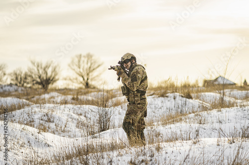 equipped army soldier Man in the winter khaki camouflage is patrolling or patrol field territory. commandos with full equipment helmet and gun watch battlefield. Modern army soldier © Oleksandr