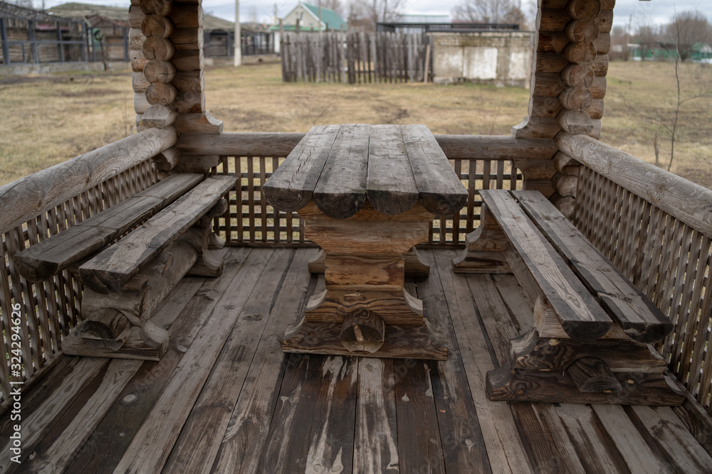 Obraz premium Wooden table with benches in amusement park. Fenced terrace with log table and benches in empty park during gloomy autumnal day