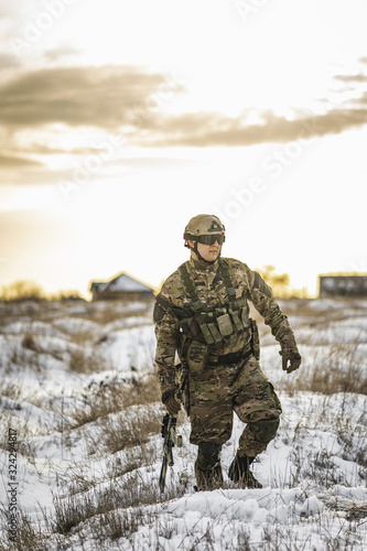 equipped army soldier Man in the winter khaki camouflage is patrolling or patrol field territory. commandos with full equipment helmet and gun watch battlefield. Modern army soldier