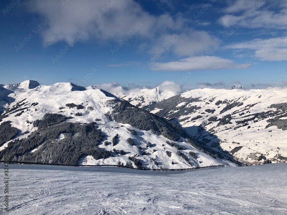 Obraz premium Empty snowy skiing slope in the mountains with blue cloudy sky