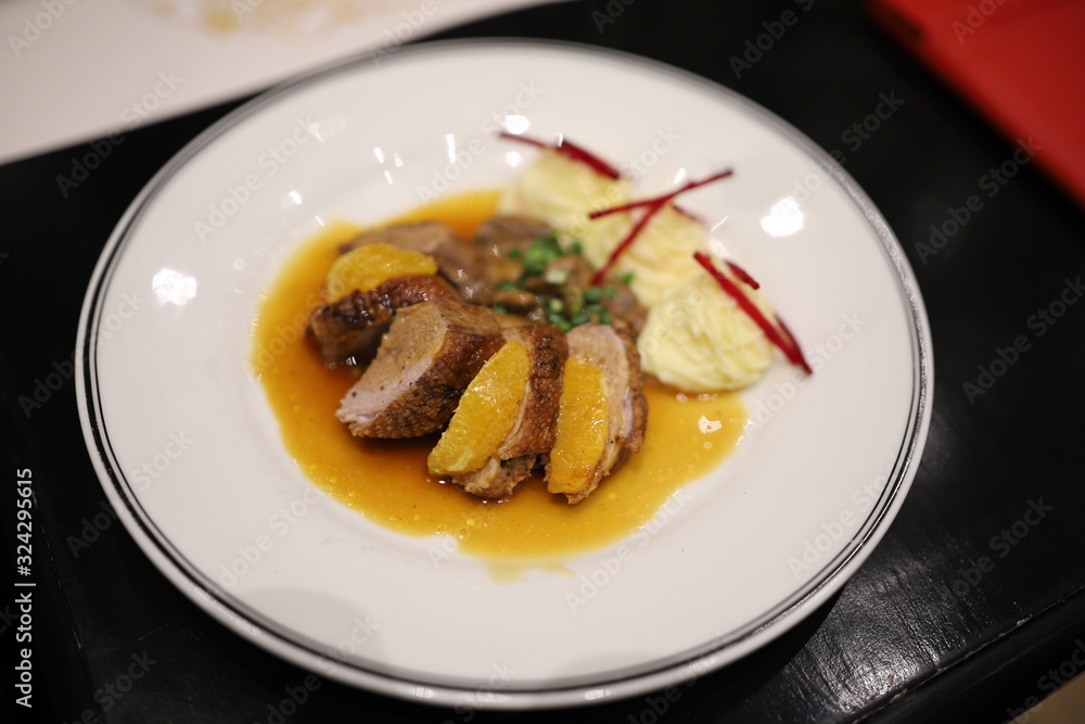 Roasted duck topped with orange sauce and mashed potatoes Decorate the dish looks appetizing on the white plate in the restaurant. Selective focus. Roasted duck topped with orange sauce and mashed potatoes Decorate the dish looks appetizing on the white plate in the restaurant. Selective focus.