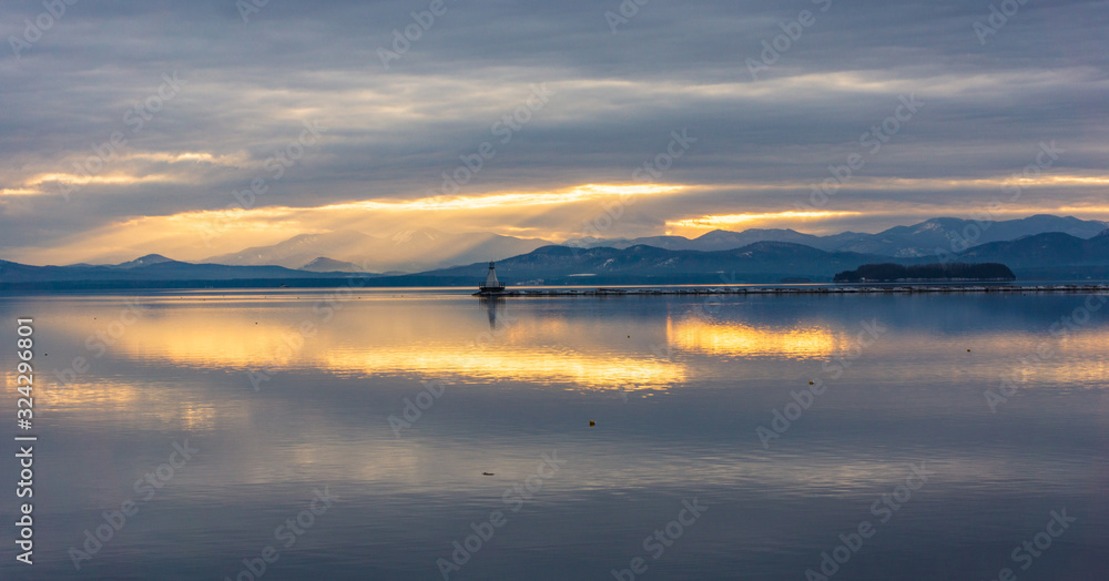  Lake Champlain in Vermont with view of vibrant sunset and the New York Adirondack mountains in winter 