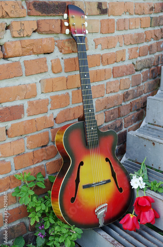 Acoustic guitar and red tulips on a brick wall background. © yrafoto
