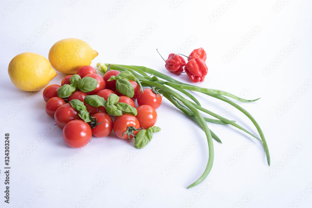 green onions, lemons, basil and fresh tomatoes on a table green onions, lemons, basil and fresh tomatoes on a table