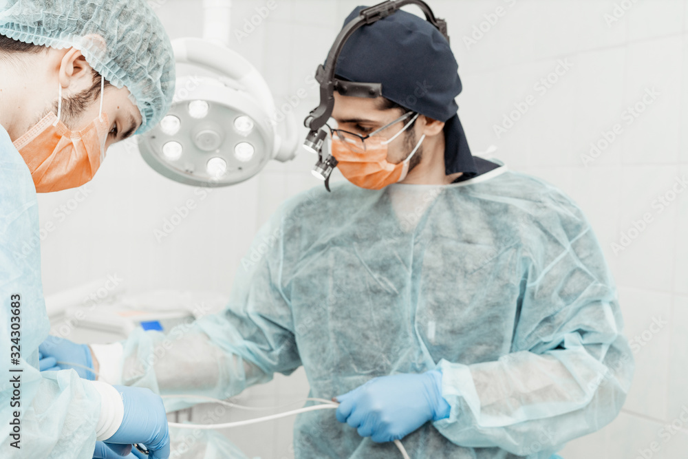 Naklejka premium Dentists will perform an operation, implant placement. Real operation. Tooth extraction, implants. Professional uniform and equipment of a dentist. Healthcare Equipping a doctor’s workplace. Dentistry