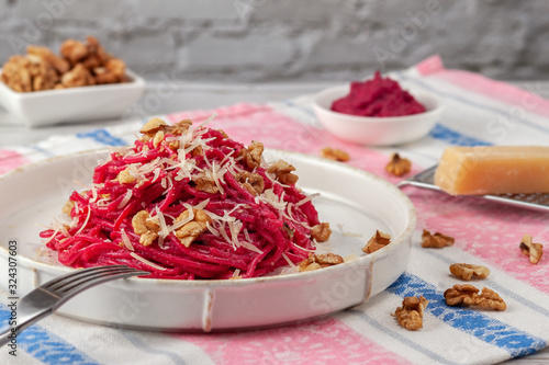 Spaghetti with beetroot pesto sauce, walnuts and parmesan on a light background photo