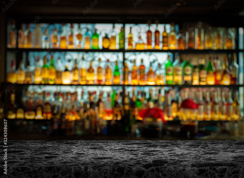 image of black marble table in front of abstract blurred background of bar lights.Blur bar or cafe restaurant with abstract bokeh light background.
