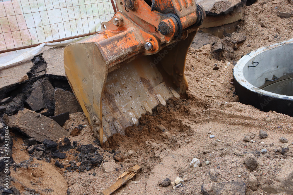 Excavator bucket in the ground. Excavator bucket removes a layer of earth and asphalt Excavator bucket in the ground. Excavator bucket removes a layer of earth and asphalt