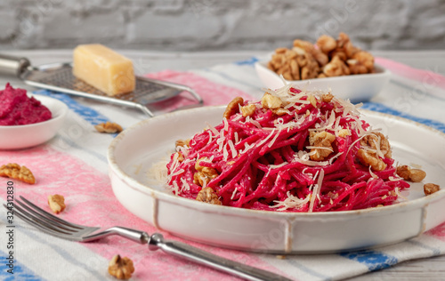 Spaghetti with beetroot pesto sauce, walnuts and parmesan on a light background photo