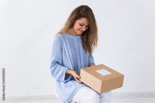 Online shopping, delivery and fashion concept - Woman sitting at home opening online clothing purchase