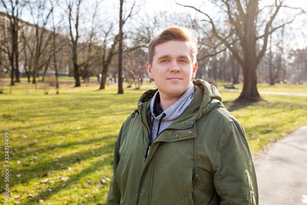 Portrait of a young man on nature background. Emotion facial expression. Happy hipster looking at camera Portrait of a young man on nature background. Emotion facial expression. Happy hipster looking at camera