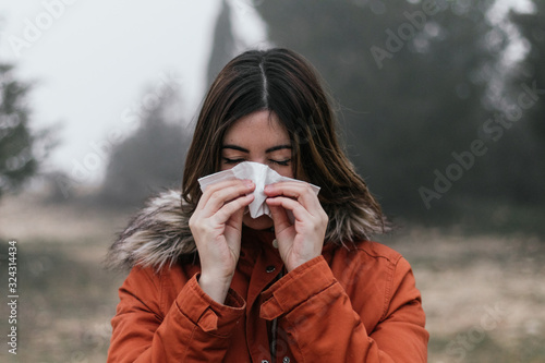 young woman blowing her nose with a handkerchief