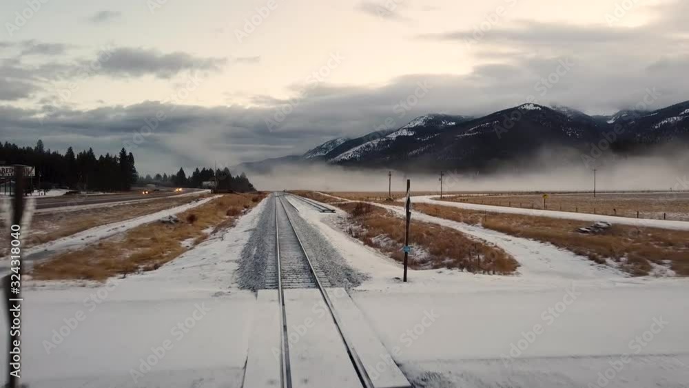 Looking down train tracks covered in snow toward fog shrouded mountain range Looking down train tracks covered in snow toward fog shrouded mountain range