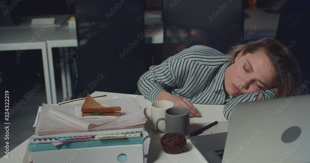 Sleepy young woman office worker lying on mess table with opened