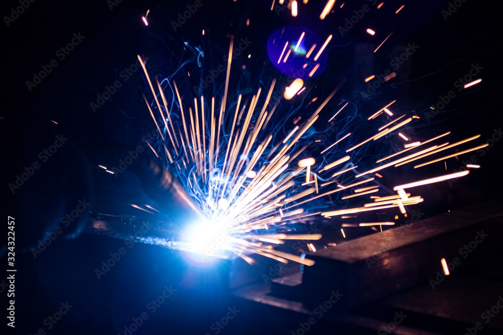 Φωτογραφία The process of welding metal in the dark with the formation of a large amount of smoke and sparks