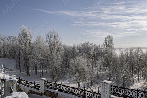 Behind the fence of the observation deck are trees in the snow and hoarfrost against the blue sky.