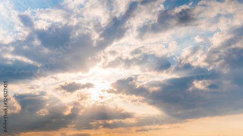 Fototapeta Naklejka Na Ścianę i Meble -  Sun beams shining through dramatic white clouds. Cloudy blue sky, warm sunrise or sunset illumination, sun lens flare. Peaceful, calm, hope, atmosphere, religion, spiritual, nature concept