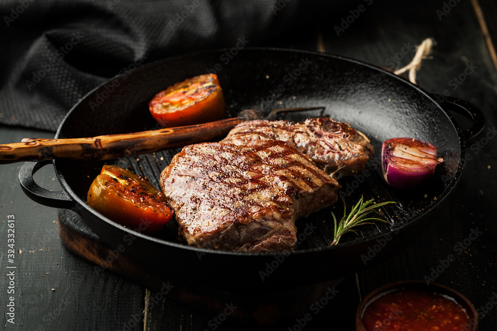 Fototapeta premium Grilled beef steak in a frying pan with vegetables
