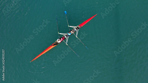 Aerial drone photo of athlete competing in canoe race in tropical lake with emerald waters