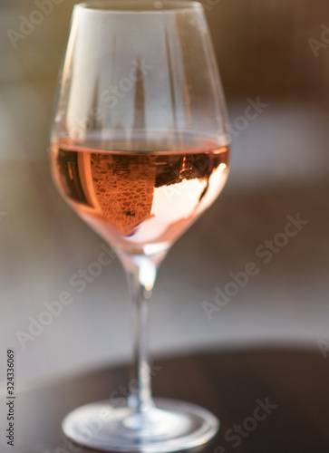 Vertical picture of glass of rose wine with reflection of old stone traditional provencal house in it. Rose wine in Provence, France. Light alcoholic drink