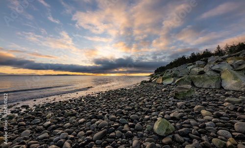 Beautiful dynamic sunrise over the coast with dramatic clouds over rocky beach on Vancouver Island, British Columbia, Canada