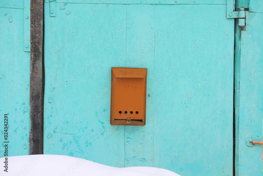 Old orange mailbox attached to a turquoise cracked wall. Old orange mailbox attached to a turquoise cracked wall.