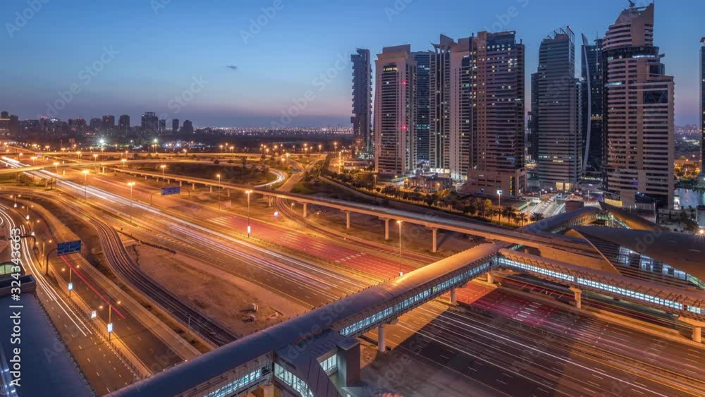 Aerial view to Sheikh Zayed road from Dubai Marina with JLT illuminated skyscrapers night to day transition timelapse, Dubai. Traffic, footbridge and metro station. United Arab Emirates Aerial view to Sheikh Zayed road from Dubai Marina with JLT illuminated skyscrapers night to day transition timelapse, Dubai. Traffic, footbridge and metro station. United Arab Emirates