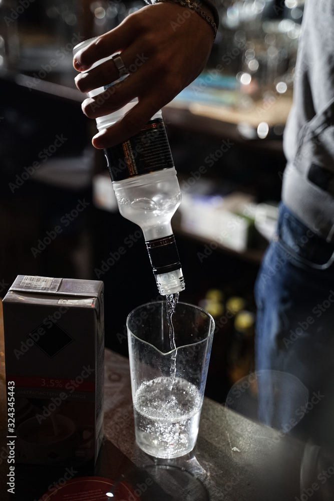 bartender pour vodka into a transparent carafe