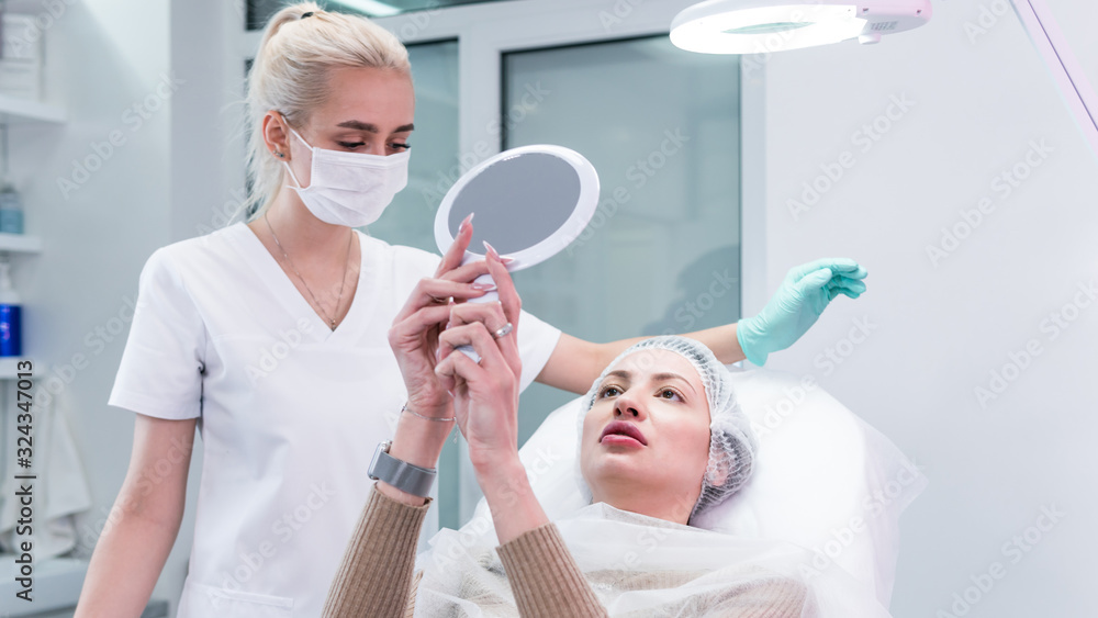 The young beautician doctor preparing to making injection in female lips. The doctor cosmetologist makes lip augmentation procedure. The young beautician doctor preparing to making injection in female lips. The doctor cosmetologist makes lip augmentation procedure.