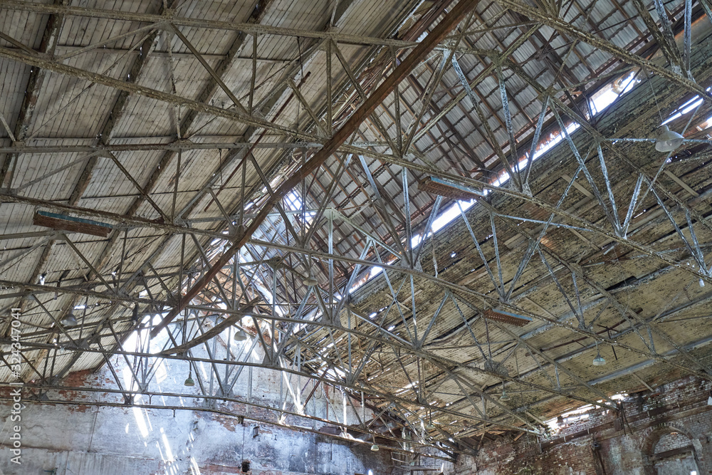 Old and dangerous roof at an abandoned factory. Metal construction of a holey roof of an abandoned factory
