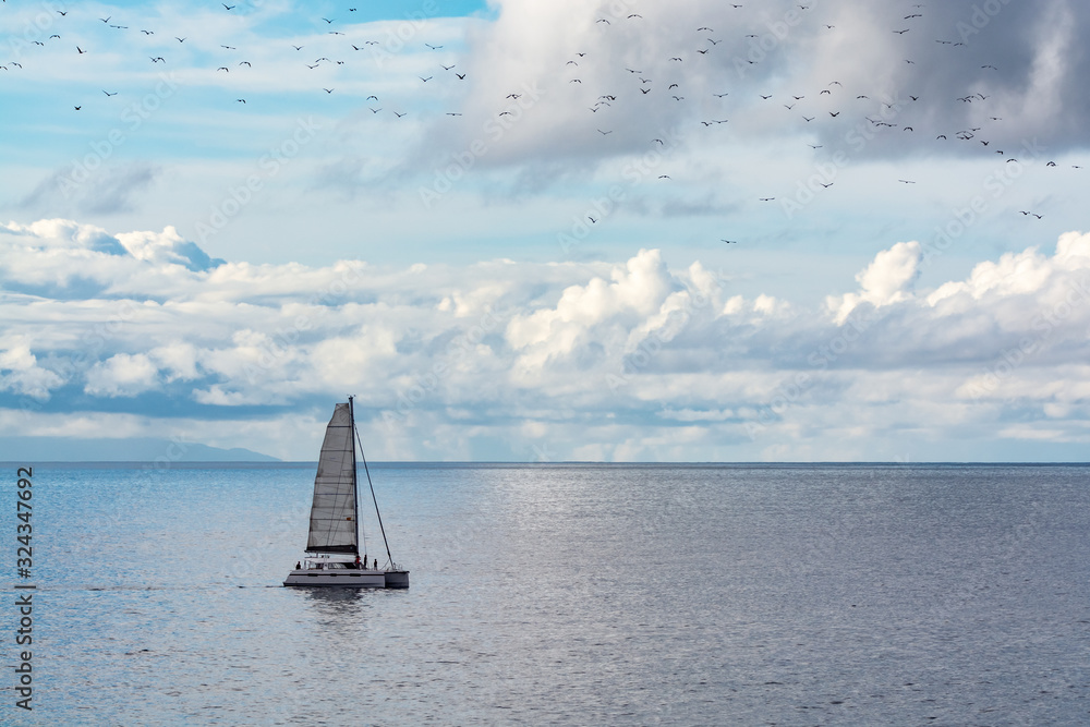 Seascape with one sail boat, cloudy sky and waves of Atlantic ocean