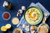 Chickpea hummus and various ingredients on a dark blue wooden background