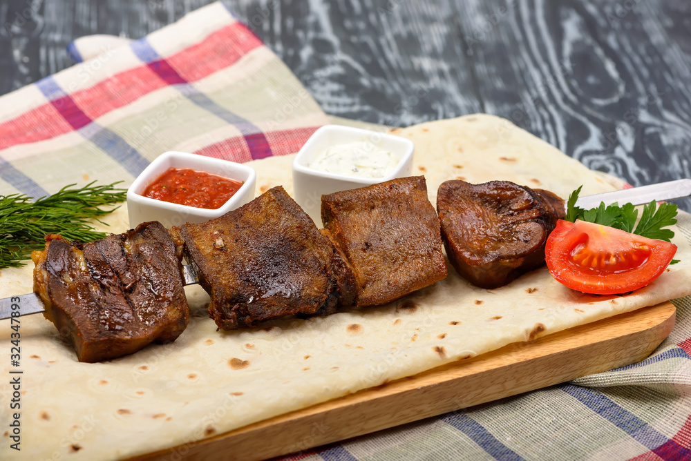 grilled beef kebabs with vegetables and sauces on lavas