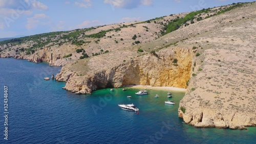 Cliffed coast of Croatian island Krk with secluded sandy beach Golden Bay and luxury yachts floating in the calm lagoon photo