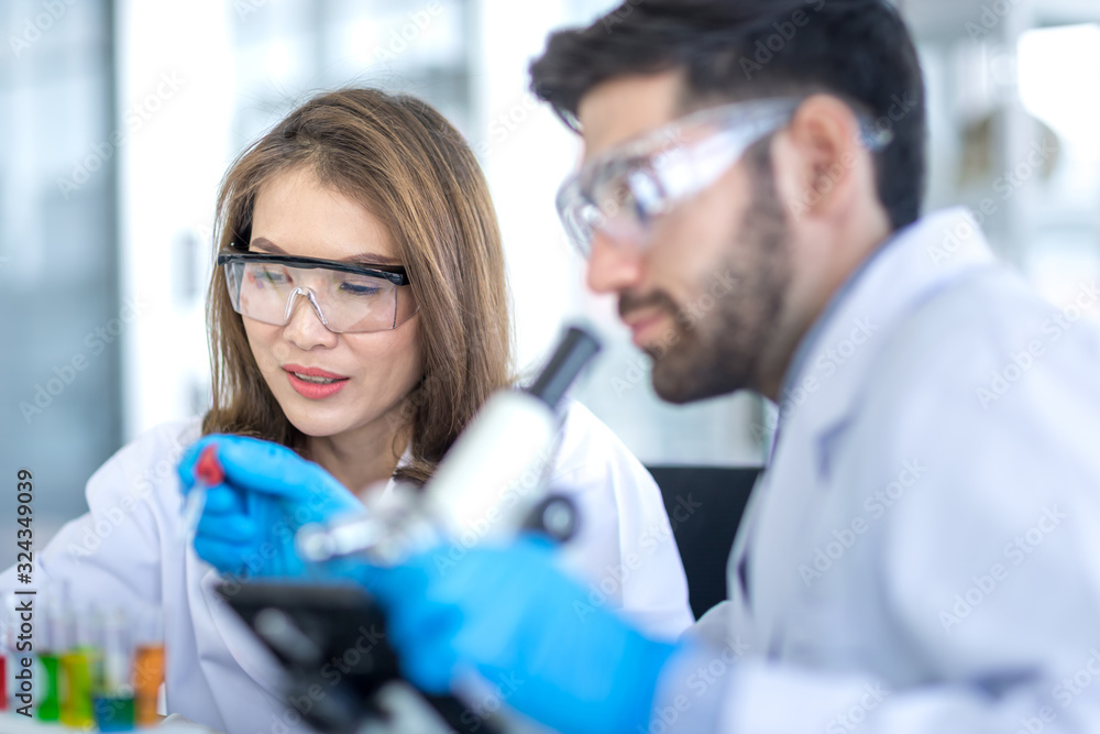 Male scientists and white female scientists are experimenting with chemicals in the laboratory. Concept, The scientists wear white protective clothing is experimenting with drug anti- Coronavirus Male scientists and white female scientists are experimenting with chemicals in the laboratory. Concept, The scientists wear white protective clothing is experimenting with drug anti- Coronavirus