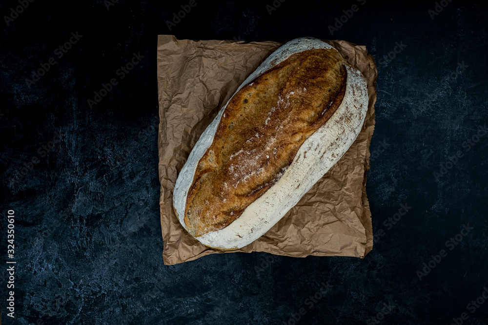 High angle close up of freshly baked loaf of bread on black background.
