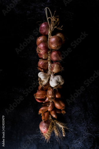 High angle close up of string of onions and garlic on black background. photo