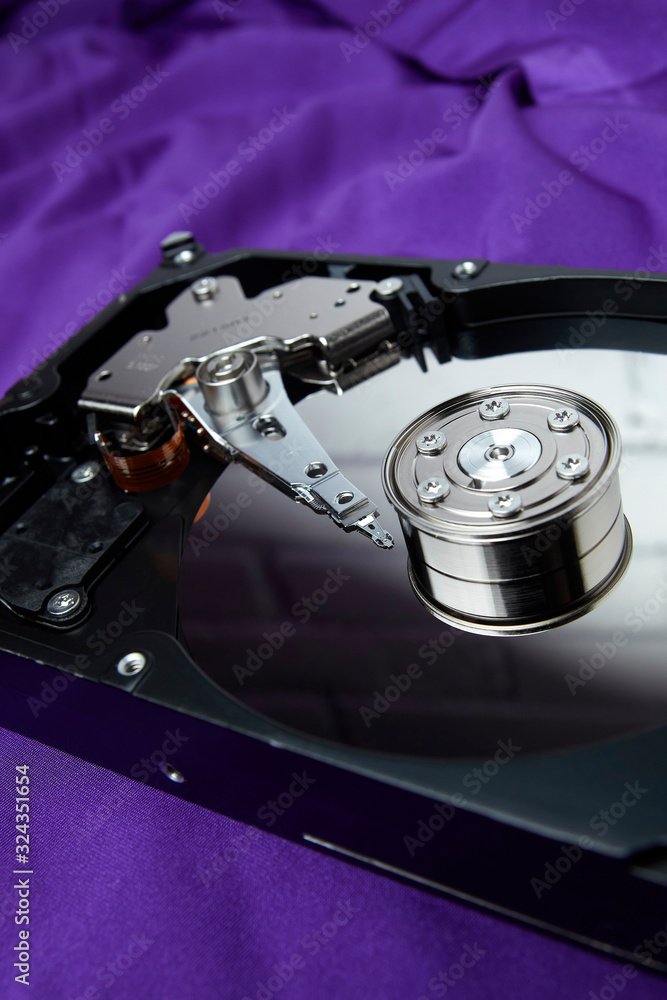 Opened hard drive from the computer hdd disk drive with mirror effects on violet background. Disassembled hard drive from the computer Opened hard drive from the computer hdd disk drive with mirror effects on violet background. Disassembled hard drive from the computer