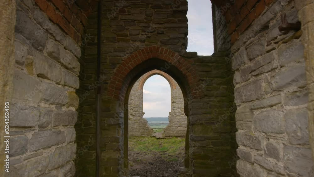 Medium low angle still shot of ancient church building ruins, and countryside landscape view through arched wall, Scotland, UK Medium low angle still shot of ancient church building ruins, and countryside landscape view through arched wall, Scotland, UK