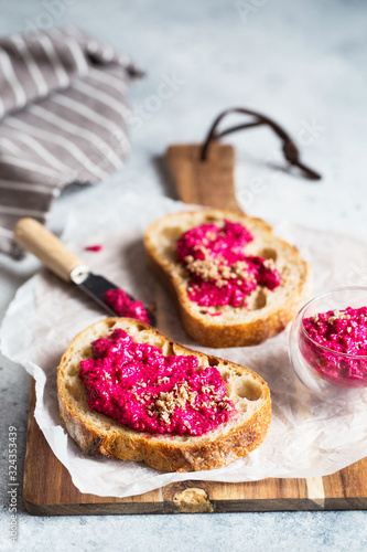 Bruschetta with Beetroot hummus decorated with chopped nuts and microgreen. Vegan recipes, plant-based dishes. Green living concept. Organic food. Vegetarian cuisine. Bread with pink dip