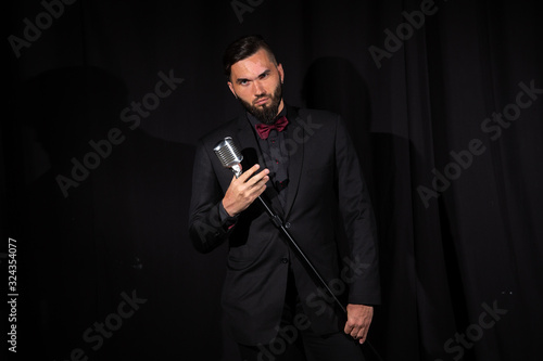 Serious male singer with microphone on black
