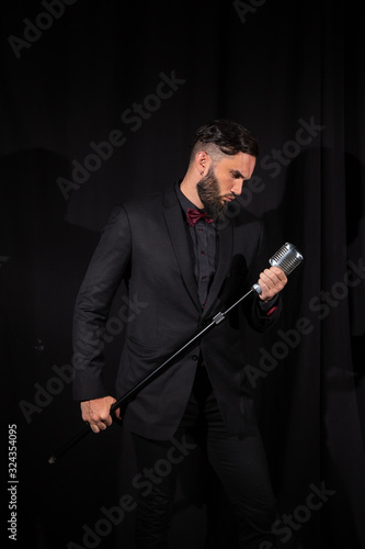 Serious male singer with microphone on black