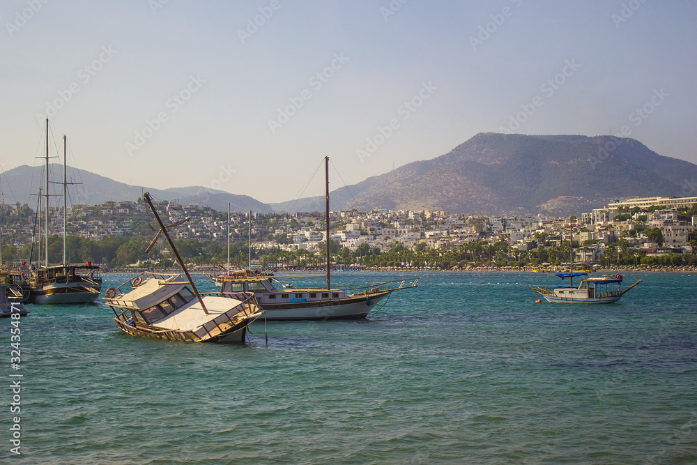 View on luxury yachts, ships and sailing boats near the shores of blue Aegean sea, moored on Bodrum port, Mugla, Turkey. Turkish summer vacation, water activity