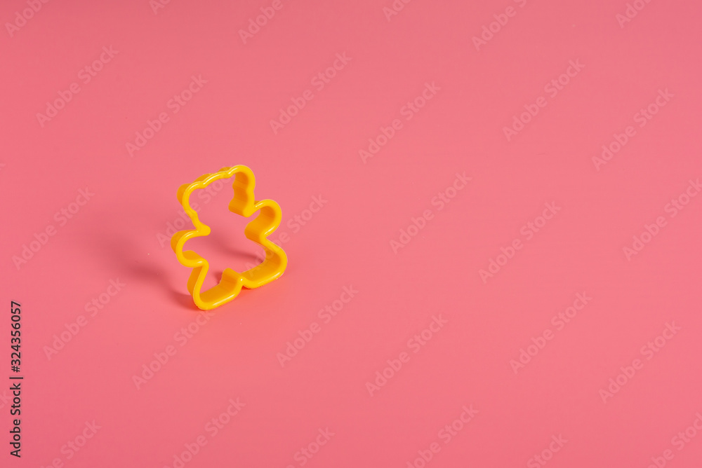Yellow plastic cookie cutter for making cookies in the shape of a teddy bear on a pink background. Culinary concept. Flat lay with copyspace. Yellow plastic cookie cutter for making cookies in the shape of a teddy bear on a pink background. Culinary concept. Flat lay with copyspace.