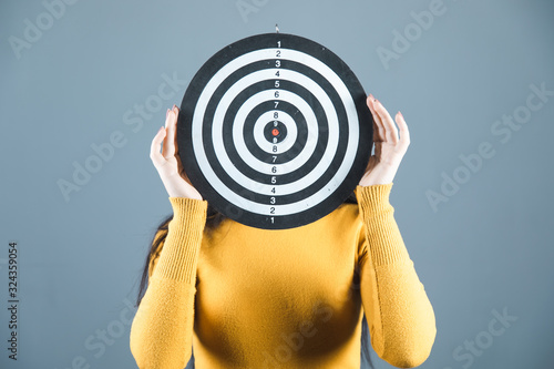 Woman covers face with target on grey background photo