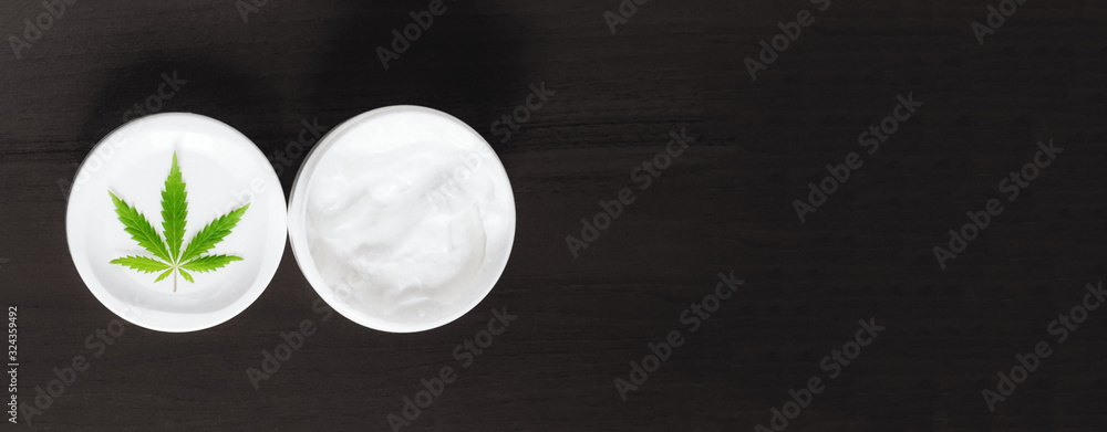 Organic natural cannabis cream leaf CBD panorama with copy space for your design or text on dark background. Concept of herbal alternative medicine, CBD. Jar of ecological hemp white lotion Organic natural cannabis cream leaf CBD panorama with copy space for your design or text on dark background. Concept of herbal alternative medicine, CBD. Jar of ecological hemp white lotion