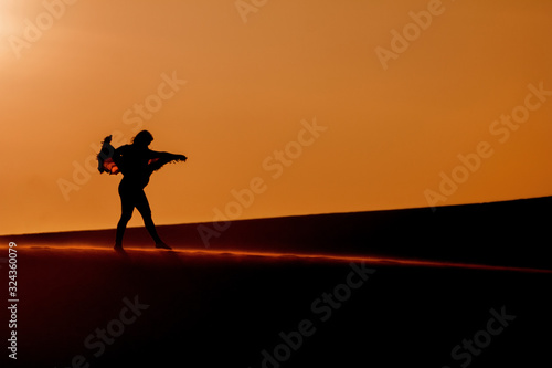 Pregnant woman walking over a dune